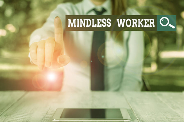 Word writing text Mindless Worker. Business concept for Having no intelligent purpose Showing little attention Female business person sitting by table and holding mobile phone. - Φωτογραφία, εικόνα
