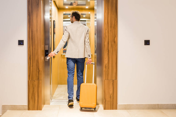 Modern businessman entering the elevator with luggage. Business and travel concept. - Fotografie, Obrázek