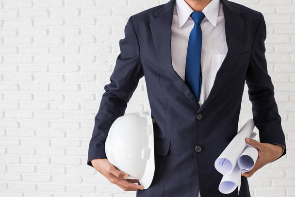 портрет инженера, держащего белый шлем и строительные отпечатки
 - Фото, изображение