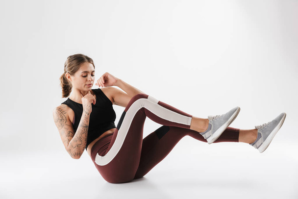 Image of attractive woman in sportswear training and doing criss cross crunches isolated over white background - Φωτογραφία, εικόνα