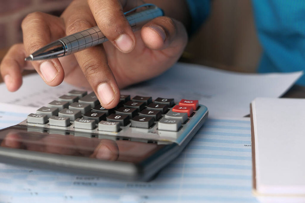 Крупним планом рука людини використовує калькулятор на столі
  - Фото, зображення