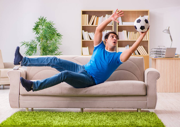Ο άνθρωπος που βλέπει ποδόσφαιρο στο σπίτι κάθεται στον καναπέ - Φωτογραφία, εικόνα