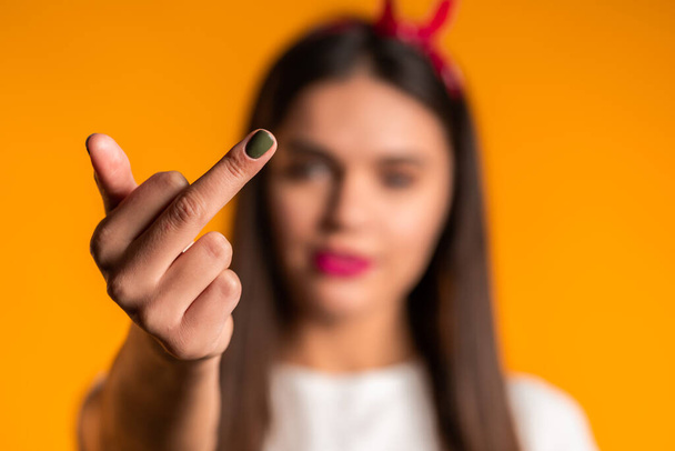 Young pretty woman on yellow background showing middle finger - gesture of fuck. Expression negative, aggression, provocation. - Foto, Imagen