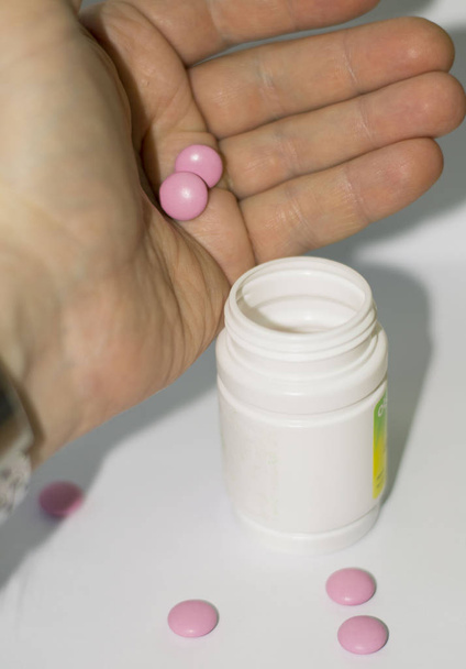 pilules roses sur fond blanc. pilules dans un bocal blanc. Vitamines, suppléments nutritionnels pour la santé de l'homme
. - Photo, image