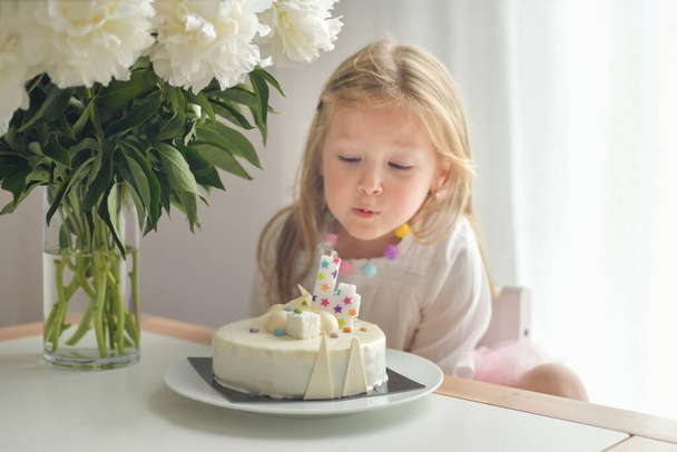 A girl of 4 years old making wish blowing candles on a cake - Фото, изображение