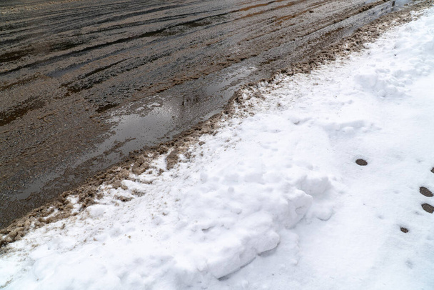 Calle de la ciudad cubierta de nieve y pistas de neumáticos sucios y senderos ligeros en invierno, fondo panorámico
 - Foto, Imagen