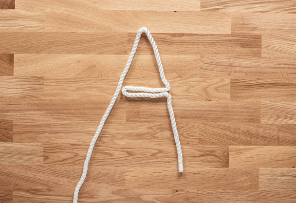 Το γράμμα Α σχηματίζεται με λευκό σχοινί σε ξύλινο τραπέζι - Φωτογραφία, εικόνα