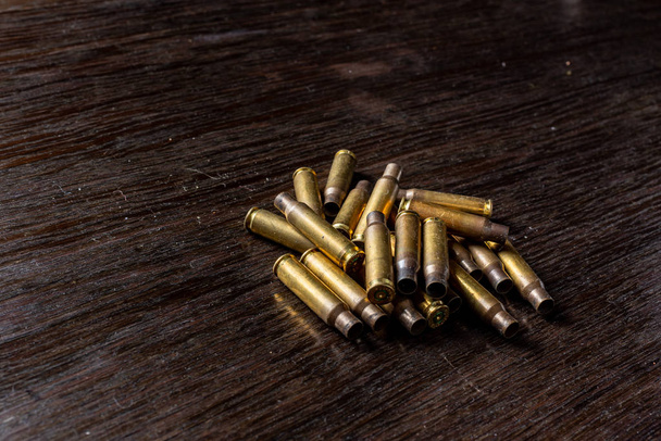 Leere Kugelhülsen auf einem dunklen Holztisch. - Foto, Bild