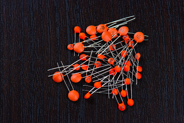 Uma pilha de capacitores de cerâmica laranja no fundo preto
. - Foto, Imagem