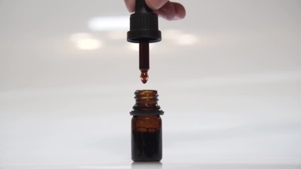 Ręka powoli napełniająca butelkę szklanego leku pipetą. CBD Konopie Olej przemysł medyczny - Materiał filmowy, wideo
