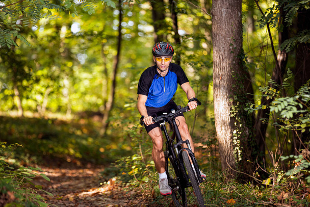 Genç sporcu dağ bisikletçisi ormanda dağ bisikleti pratiği yapıyor. - Fotoğraf, Görsel