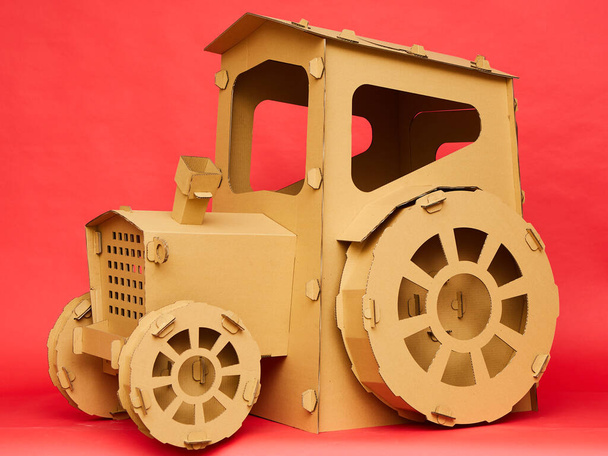 The cardboard tractor on red background. Agricultural and eco concept - Foto, immagini