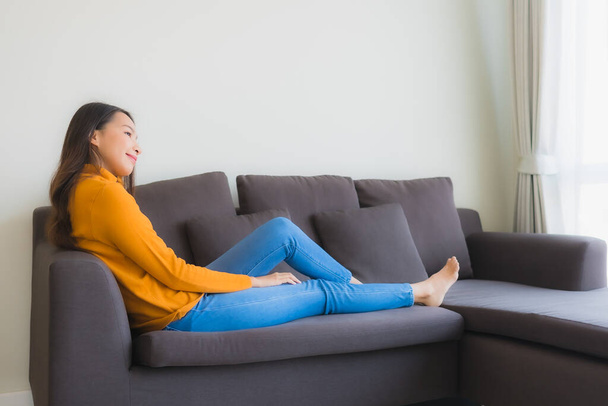 Retrato jovem asiático mulher feliz relaxar sorriso no sofá cadeira com travesseiro na sala de estar interior - Foto, Imagem