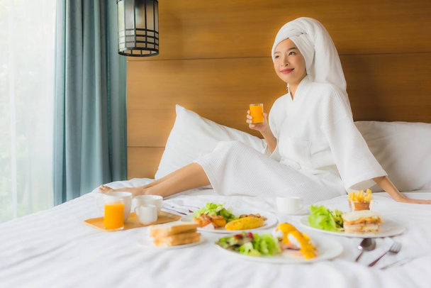 Retrato joven mujer asiática en la cama con desayuno en el interior del dormitorio - Foto, imagen