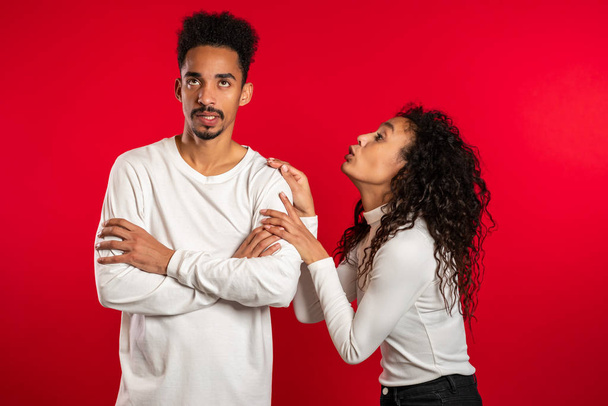 Cute african young woman begging her boyfriend or husband about something over red background. - Fotó, kép