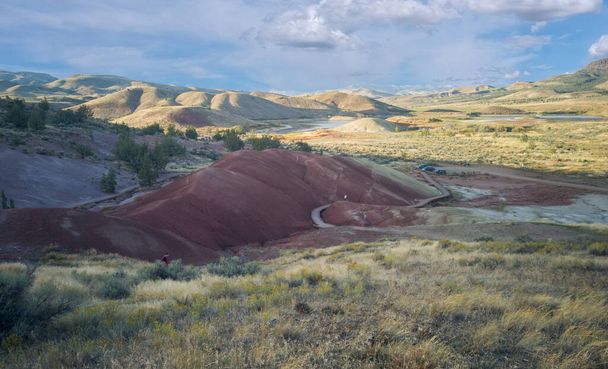 Oregon 'daki John Day Fosil Yatakları Koyu Boyalı Koyu Yolu' nda büyük beyaz bulutları ve mavi gökyüzü olan güzel yarı çöl arka planına sahip nefes kesici kırmızı ve beyaz fosil yataklarıyla nefes kesici kırmızı ve beyaz kil fosil yatakları. - Fotoğraf, Görsel