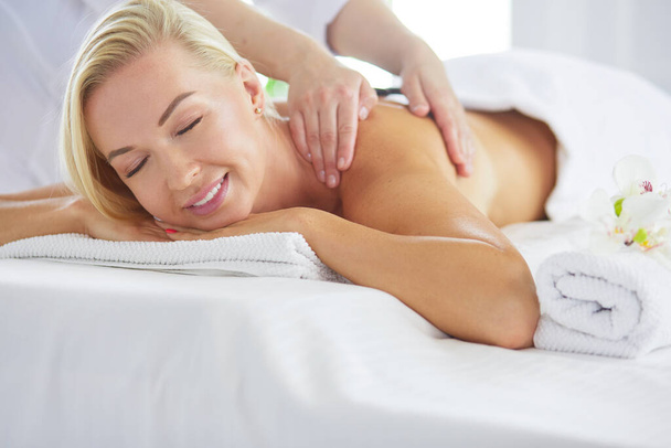 Young woman enjoying massage in spa salon - 写真・画像
