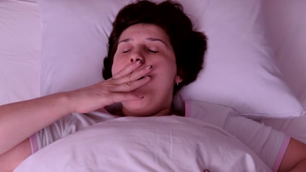 Top view. Adult Woman with red hair yawns in bed in the morning. - Filmagem, Vídeo