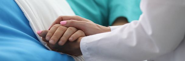 Женщины-врачи держат руку мужчины в медицинской больнице
 - Фото, изображение