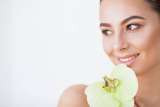Belleza cara de mujer con piel sana y planta verde
 - Foto, imagen