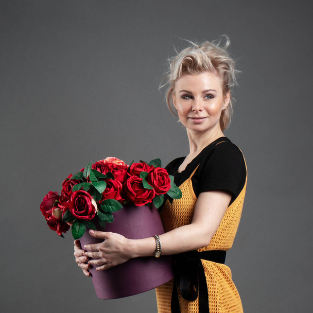 Портрет красивої молодої блондинки кавказької усміхненої жінки, що тримає кошик, повний квітів у студії
 - Фото, зображення