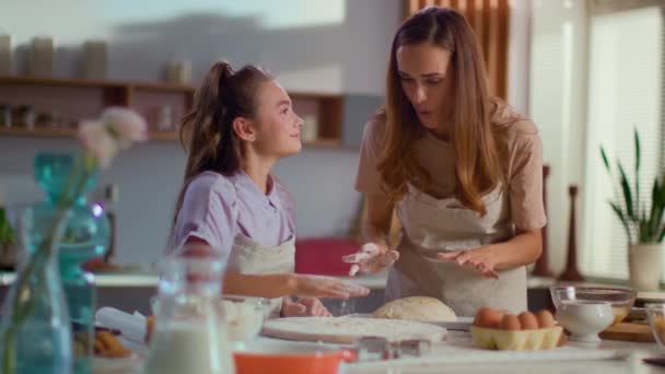 Mother and daughter smearing noses each other with flour on kitchen - Felvétel, videó