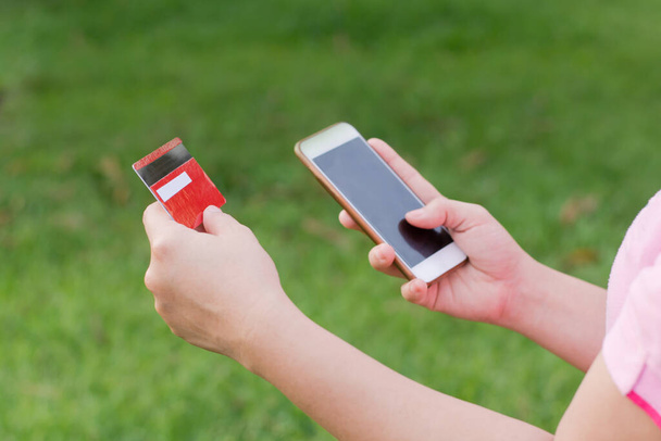 жіночі руки тримають кредитну картку і використовують мобільний телефон для онлайн-покупки
  - Фото, зображення