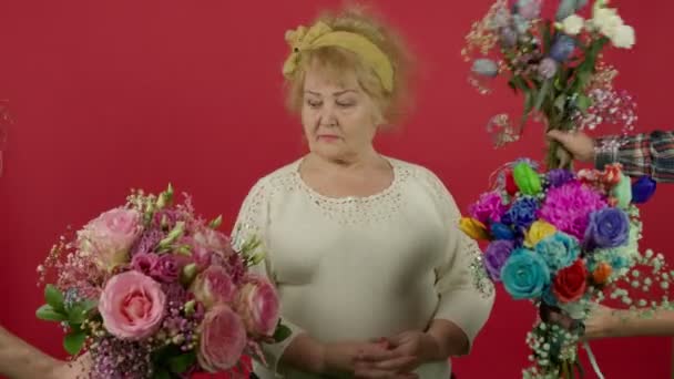 Idősebb nő nézi a virágok, mosolygós és szaglászó csokor - Felvétel, videó