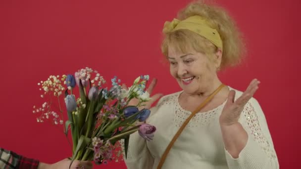 Boldog idős nő vesz tulipán csokor mosollyal - Felvétel, videó