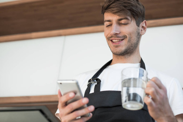 attractive young man reading a recipe on his smartphone - Photo, Image