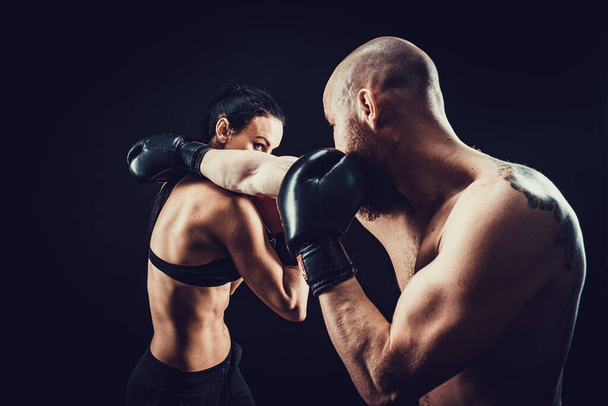 Shirtless Woman exercising with trainer at boxing and self defense lesson, studio, smoke on background. Female and male fight - Photo, Image