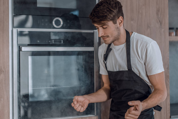 frustrated young man standing near broken oven - Photo, Image