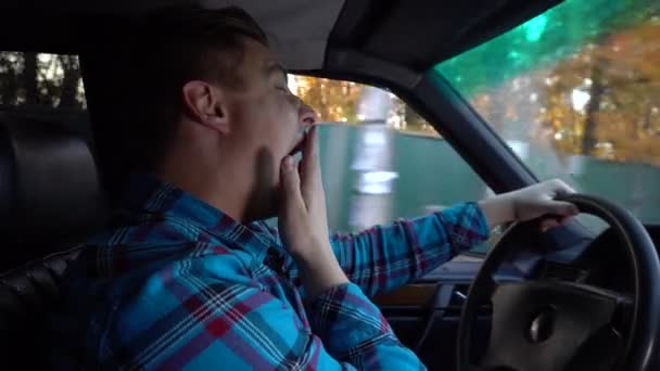 A young man drives a car and falls asleep. Daylight hours. The driver is actively struggling with sleep. Driver side view - Záběry, video