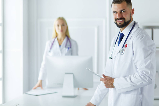 Ευτυχισμένη ιατρική ομάδα γιατρών, άντρας και γυναίκα, απομονωμένος σε λευκό φόντο σε ένα δωμάτιο νοσοκομείου. - Φωτογραφία, εικόνα