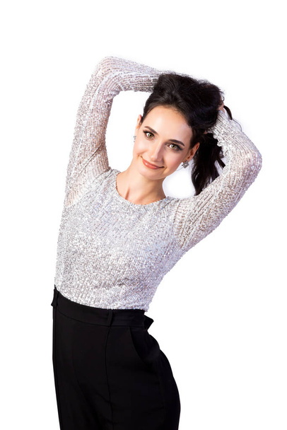 attractive woman in styling and bright makeup in a beautiful top with sparkles, black trousers and sandals smiling and looking at the camera on a white isolated background. Female portrait of an attractive woman - Фото, изображение