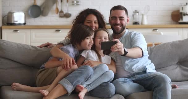 Hymyilevä isä, jolla on matkapuhelin, ottaa perheen selfie
. - Materiaali, video