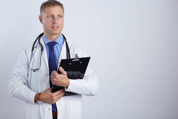 Médico varón de pie con carpeta, aislado sobre fondo blanco - Foto, imagen