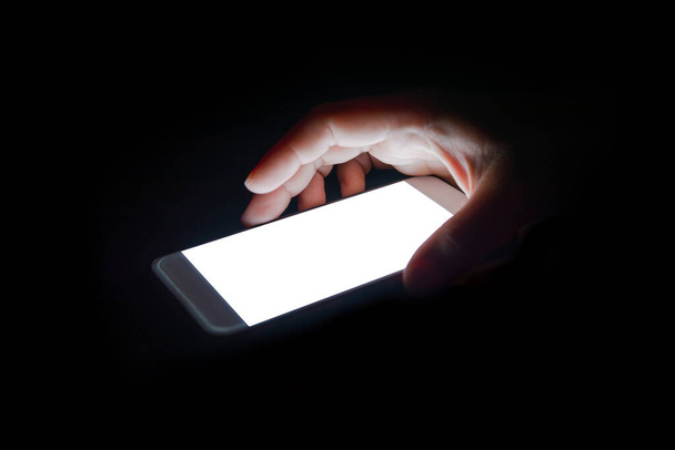 λευκό φως από το smartphone αντανακλά το χέρι σας τη νύχτα στο dark.blank οθόνη για κείμενο και σχεδιασμό - Φωτογραφία, εικόνα
