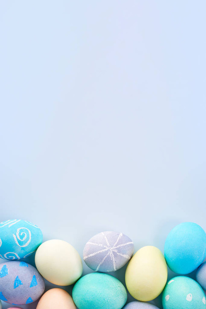 Ovos de Páscoa coloridos tingidos por água colorida com belo padrão em um fundo azul pálido, conceito de design de atividade de férias, vista superior, quadro completo
. - Foto, Imagem