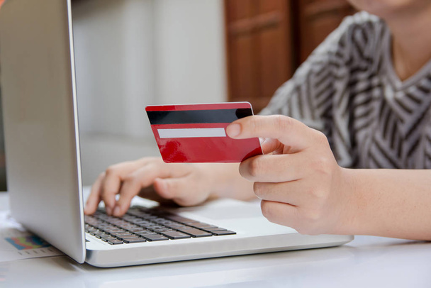 ラップトップを使用してオンラインショッピングやインターネットバンキングでクレジットカードを保持している女性. - 写真・画像