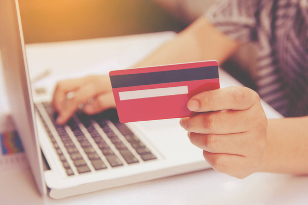 woman useing laptop and holding credit card with online shopping or internet banking online. - Photo, Image