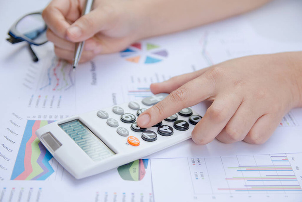 zbliżenie kobieta za pomocą kalkulator na papierowym wykresie dane z robi finanse w biurze. - Zdjęcie, obraz
