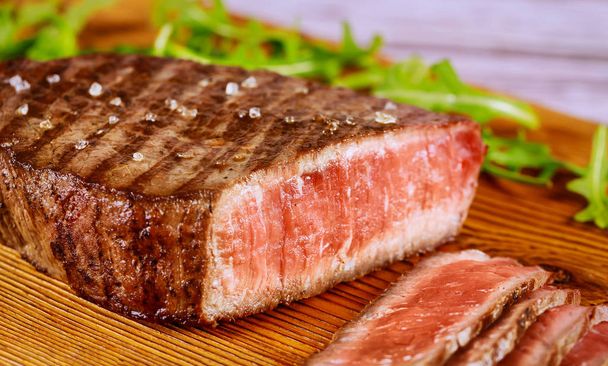 Steak de boeuf angus rare grillé avec du sel de mer sur une planche de bois. Gros plan
. - Photo, image