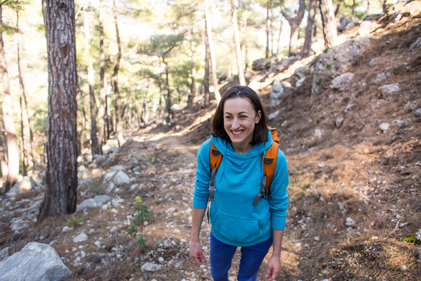 少女が森の中を歩いている。山の中でハイキング。女性が公園を歩いている。積極的なライフスタイル。女性が山の中でキャンプに行く. - 写真・画像