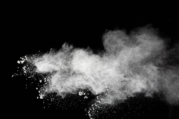 Παγώστε την κίνηση των λευκών σωματιδίων σκόνης βουτιά σε μαύρο φόντο.Λευκά σύννεφα έκρηξη σκόνης. - Φωτογραφία, εικόνα