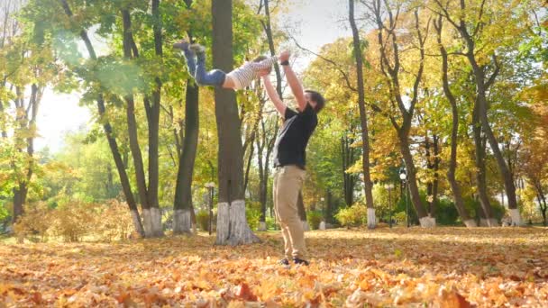 4k slow motion video of happy young father playing and throwing his little son in the air at autumn park - Filmmaterial, Video