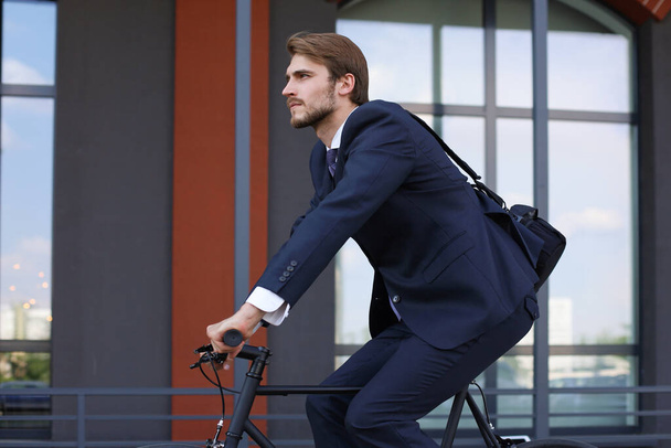 Handsome businessman riding bicycle to work on urban street in morning - Foto, Imagem