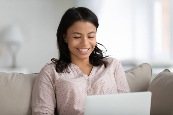 Smiling biracial woman browsing internet on laptop - Fotó, kép