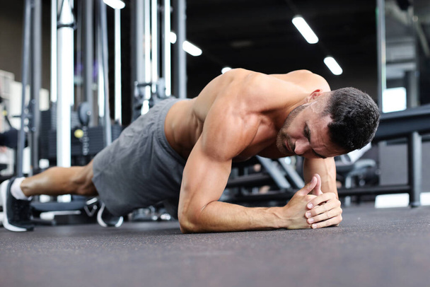 Portrait of a fitness man doing planking exercise in gym - Foto, afbeelding