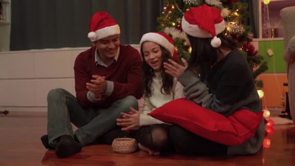 Parents and children clap their hands and sing a Christmas song before giving a gift to their daughter on Christmas Day. - Filmagem, Vídeo